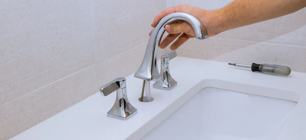 Plumber providing drain cleaning service under a bathroom sink