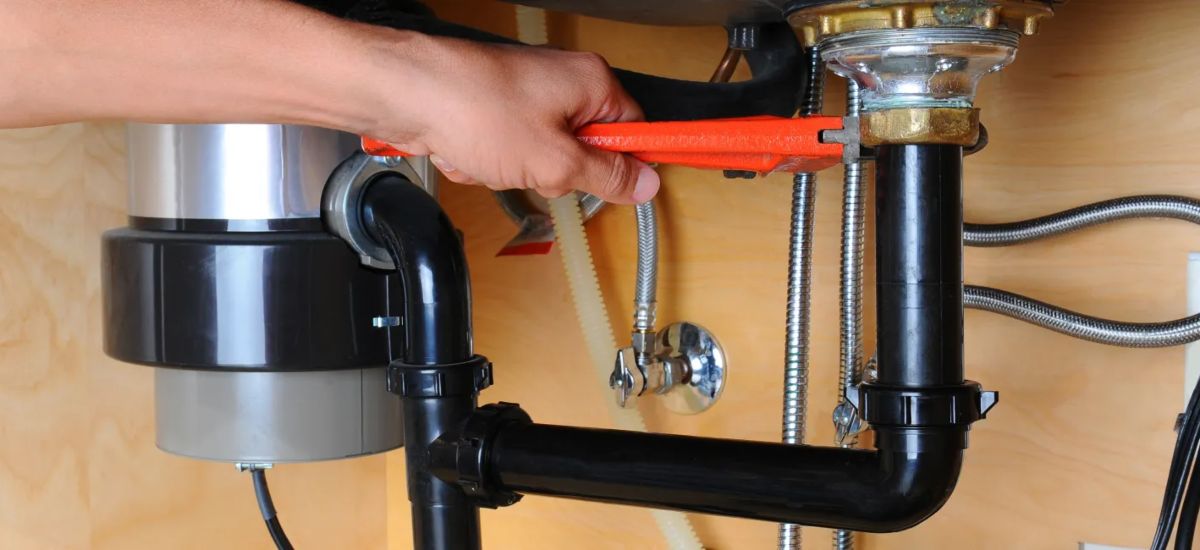 Plumber providing drain cleaning service under a bathroom sink