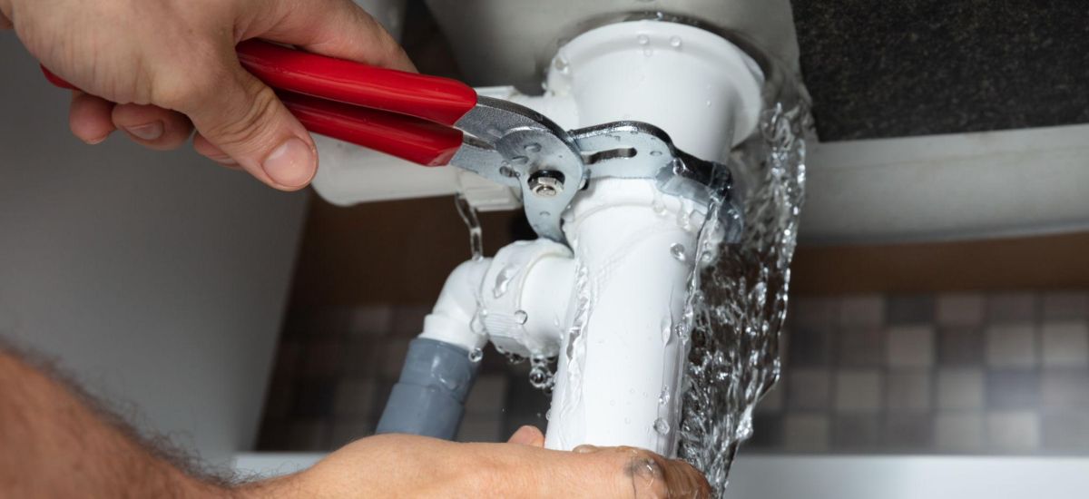 Plumber providing drain cleaning service under a bathroom sink